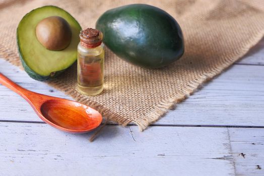 Top view of oil and slice of avocado on wooden table .