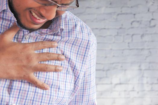 young man suffering pain in heart and holding chest with hand .