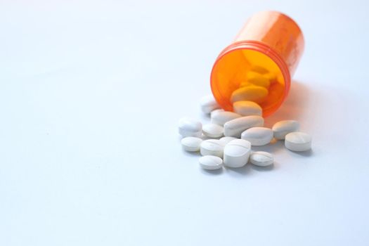 close up of white pills spilling on white background .