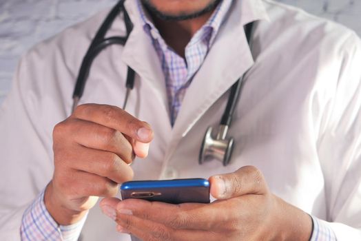 Doctor in face mask using smartphone in the hospital