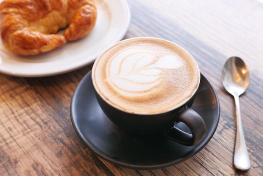 Coffee and croissant on wooden table, top view