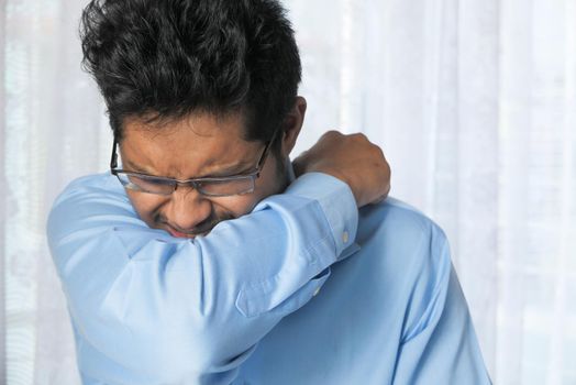 Young ill man covering her nose and mouth with arm