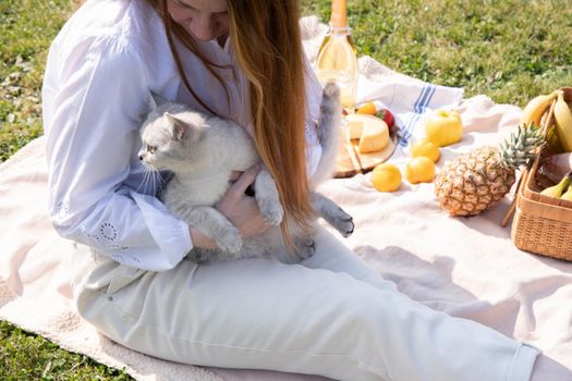 a young woman in a white shirt is resting on a picnic with her pet kitten, rest from worries and household chores, parks and recreation areas,. High quality photo