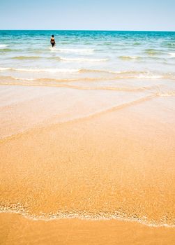 Unidentified man and the bubble of sea wave on the beach