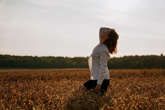 Silhouette of woman enjoying sunset. A woman in a wheat field makes flowing movements. The concept of calmness and meditation