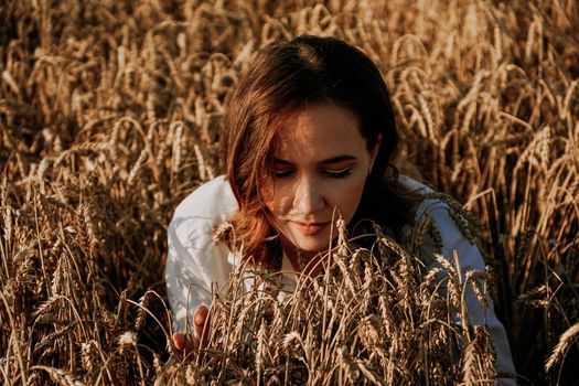 Redhead beautiful woman in a rye field. She breathes in the scent of fresh ears. Sunny day