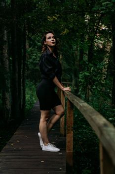 Woman in black clothes. Walk in a dark coniferous forest. Tracking and trip.