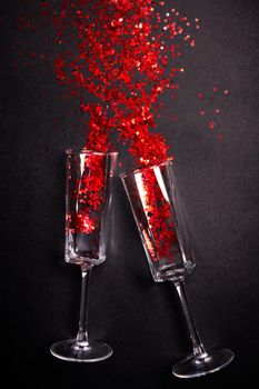 Glass with red glitter on black background,
