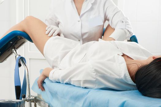 gynecologist is examine a patient who is sitting in a gynecological chair