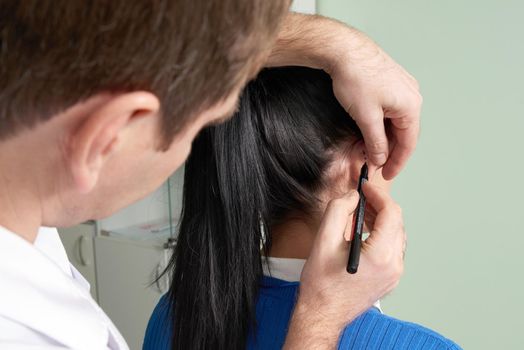 Plastic surgeon examines ear of patient before plastic surgery in hospital