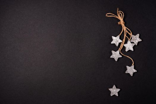 Flat lay decor with wooden stars and rope over black background, top view