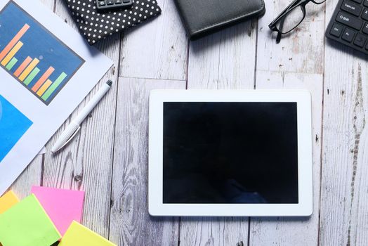 Flat composition of digital tablet and office stationary on black background .