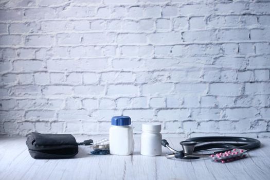 stethoscope and pills container on wooden background .