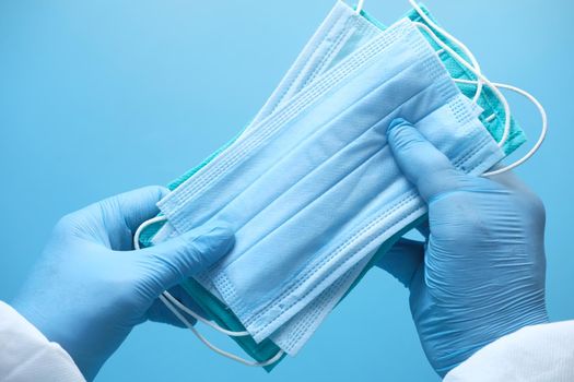 doctor hand in medical glove holding protective surgical face mask, close up .