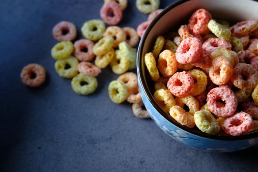 colorful ring corn flakes in a bowl on table cloth .