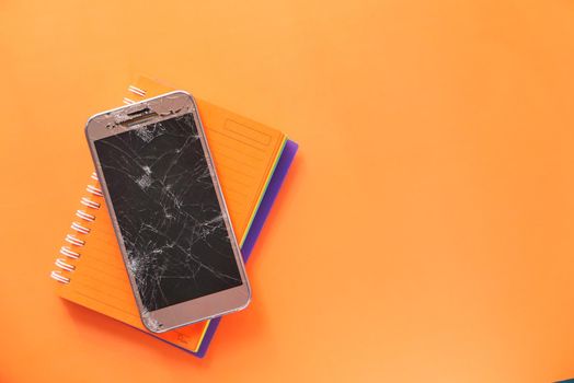 Top view of broken smart phone on color background.