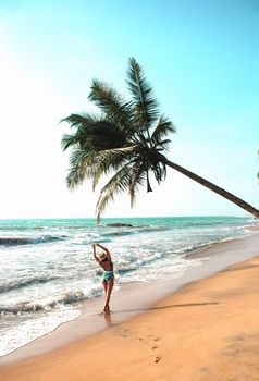 young woman stands under a palm tree on the beach . The concept of vacation and travel to the ocean. Resort on the island. beach photo, paradise vacation on the beach