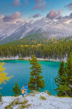 Minnewanka lake in the Canadian Rockies in Banff Alberta Canada with turquoise water, Lake Two Jack in the Rocky Mountains of Canada. a couple of men and women hiking by the lake during snow weather