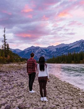 A couple of men and women watching the sunrise in Jasper, sunrise by Athabasca river Canada during Autumn. Asian women and caucasian men by the Athabasca river in the Canadian Rockies