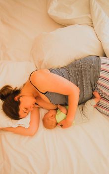 Mother and newborn baby sleep in the bed together