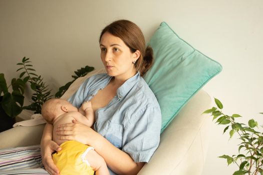 Mothed and baby at the chair. Breastfeeding in cradle position