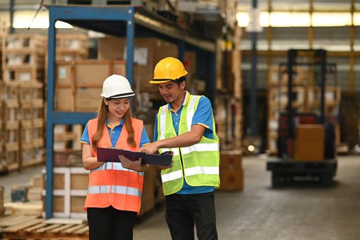 Managers and warehouse worker checking inventory in a warehouse with packed boxes on shelves in the background.