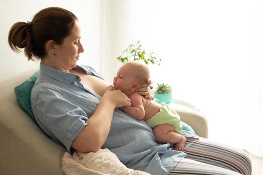 Breastfeeding in laid back position. Mothed and baby at the chair.