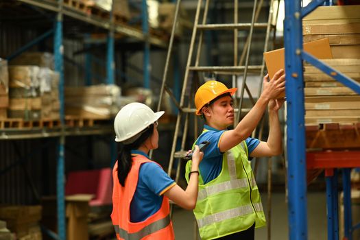 Shot of female managers and male worker checking inventory and quantity of storage product on shelf in n a large warehouse.