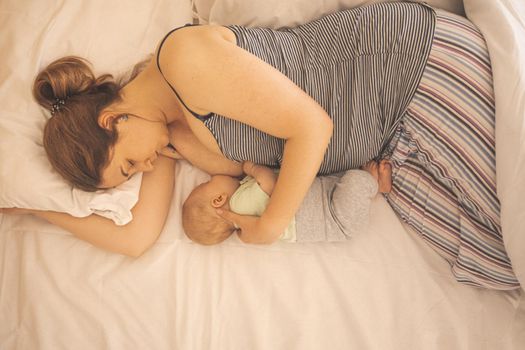Mother and newborn baby sleep in the bed together