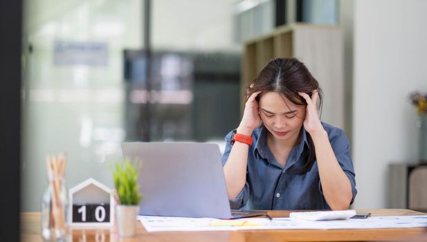 Asian women are stressed while working on laptop, Tired asian businesswoman with headache at office, feeling sick at work, copy space.