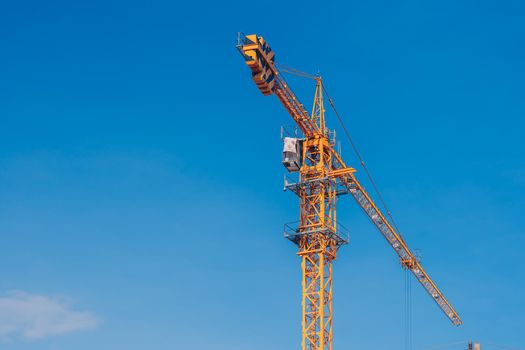 Tower Crane lattice boom hook clear blue sky sun background. Construction site work building installation.