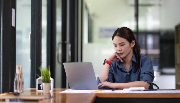 Portrait of Asian young female working on laptop at office.