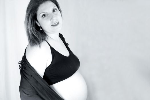 Eight month pregnant woman with bare belly. Happy emotion
