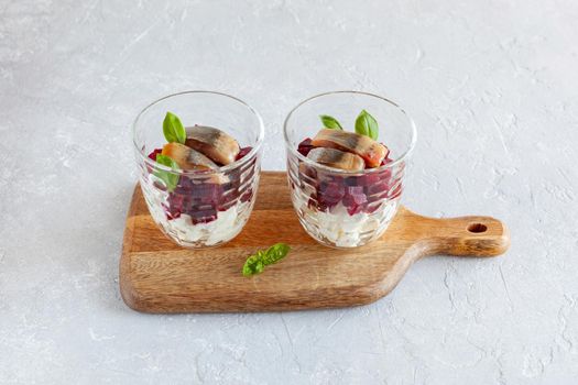 smoked salmon, beetroot and soft cheese salad served in two glasses and decorated with basil leaves