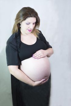 Eight month pregnant woman with bare belly. Happy emotion