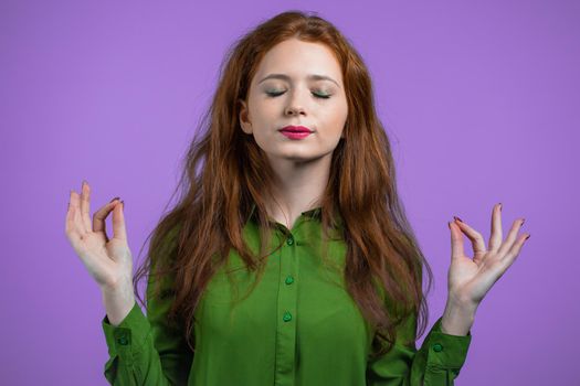 Calm woman relaxing, meditating. She calms down, breathes deeply with mudra om on violet studio background. Yoga concept. High quality