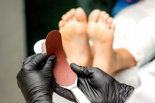The pedicurist put on a new heel file on the metal handle before the procedure of cleaning the feet in a nail salon