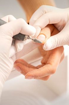Closeup of manicure master removes nail polish uses an electric nail file in a nail salon