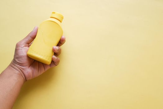 holding a mustard mayonnaise container on yellow background ,