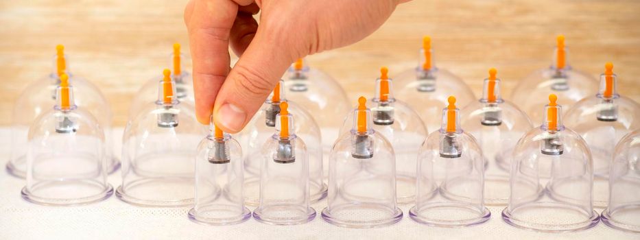 Hand of massage therapist taking vacuum cups from the table before cupping procedures