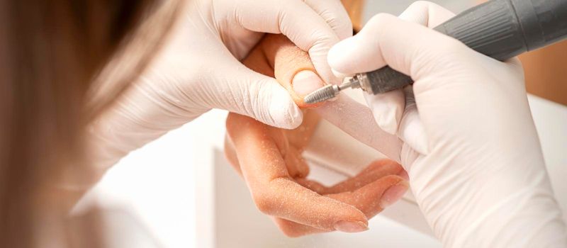 Closeup of manicure master removes nail polish uses an electric nail file in a nail salon