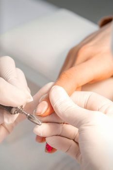 Closeup of manicure master removes nail polish uses an electric nail file in a nail salon
