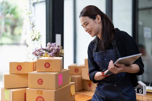Young attractive asian woman owner startup business with box at home prepare parcel delivery in sme supply chain, procurement concept
