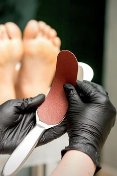 The pedicurist put on a new heel file on the metal handle before the procedure of cleaning the feet in a nail salon