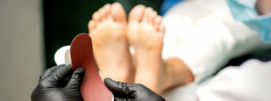 The pedicurist put on a new heel file on the metal handle before the procedure of cleaning the feet in a nail salon