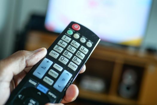 close up of man hand holding tv remote