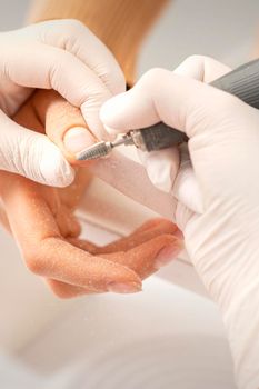 Closeup of manicure master removes nail polish uses an electric nail file in a nail salon