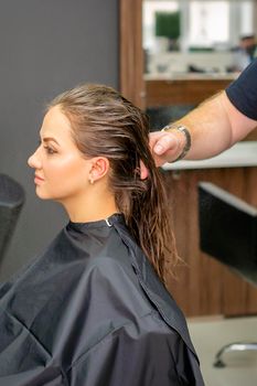 Young woman with wet long hair receiving hairstyle in a hair salon