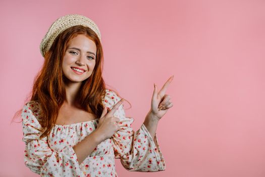 Happy smiling woman presenting and showing something isolated on pink background. Portrait of girl, she pointing with arms on her left with copy space. High quality photo