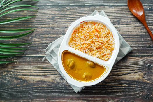 curry chicken and rice in a take away plastic packet on table .